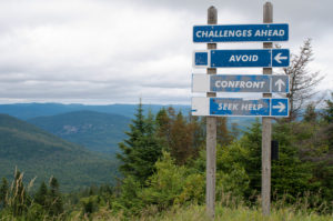 Signpost on top of the mountain warning challenges ahead and three options